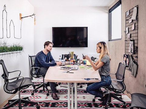 Two people work on a project together at a desk with Setu chairs. 