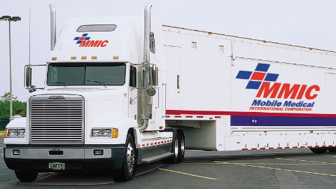 A surgery unit truck and trailer from Mobile Medical International sits in a parking lot.