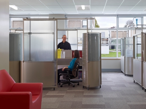 Faculty talk amidst translucent My Studio walls inside of a cubicle area.