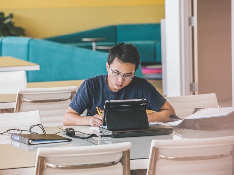 A student studies while seated at a library table.