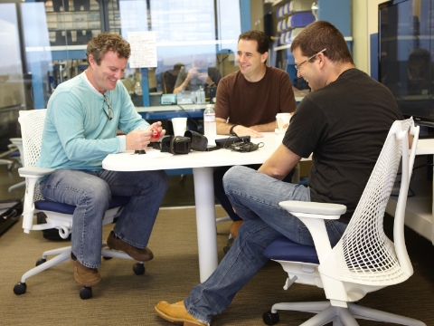 Three men sit in Sayl chairs while conversing at a table. Three men sit in Sayl chairs while conversing at a table.