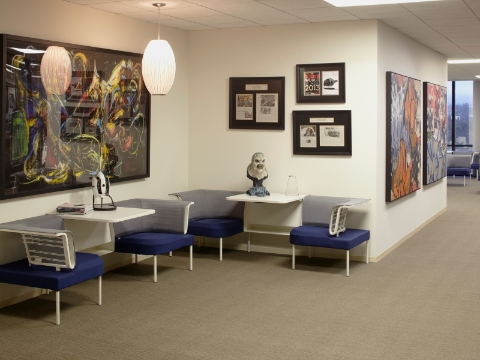 A group of Social chairs sit along a wall inside of an office lobby.