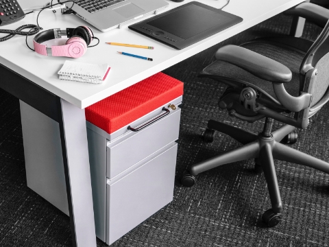 A desk setup with a laptop, pencils, headphones, and a notepad sitting out.