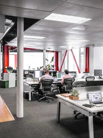 Employees sit at their computer desks while wearing headphones. Employees sit at their computer desks while wearing headphones.