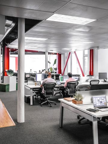 Employees sit at their computer desks while wearing headphones.