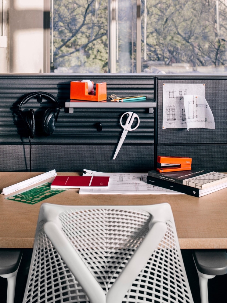 A cubicle workspace displays various office items and a pair of headphones. 