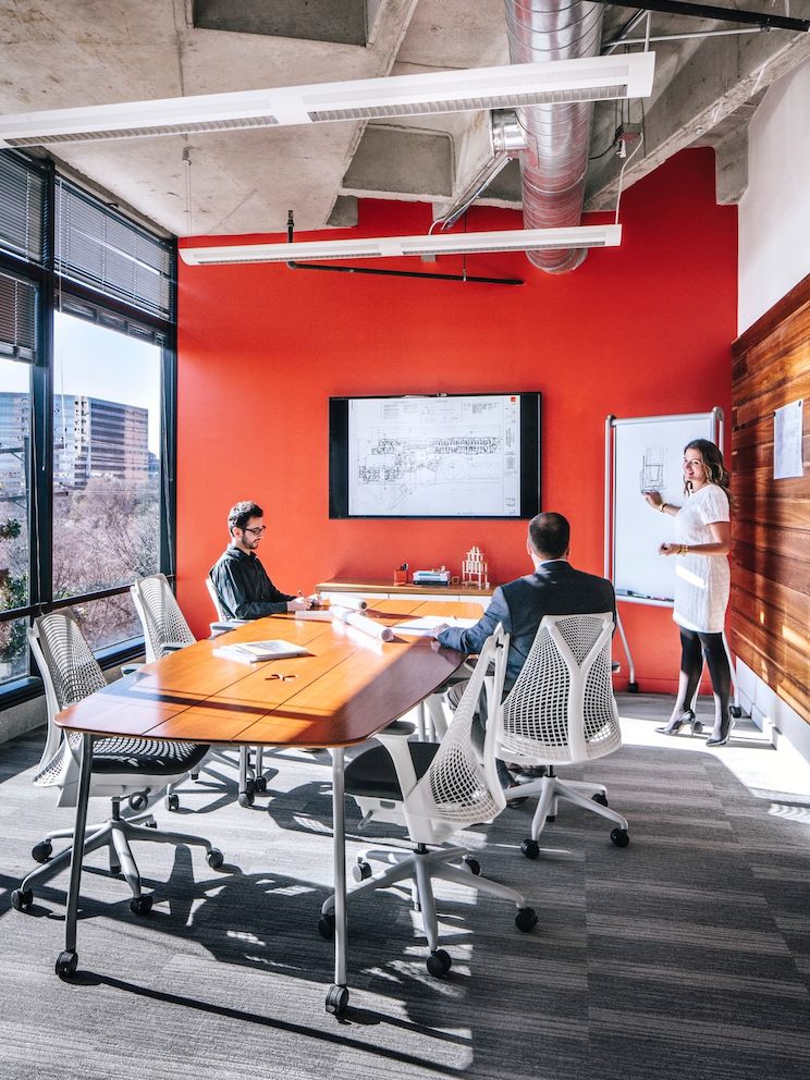 Employees converse inside of a conference room while seated in Sayl chairs. 