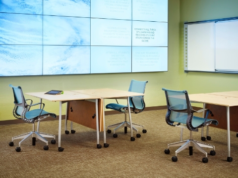 A college clasroom with tables and Setu chairs, and a video wall backdrop. A college clasroom with tables and Setu chairs, and a video wall backdrop.