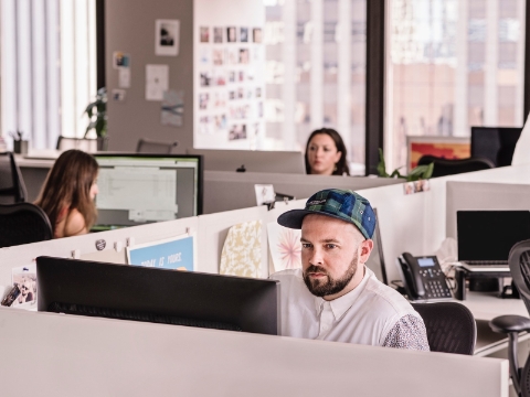 Un homme regarde son écran d'ordinateur assis dans un bureau.