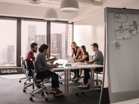 Mensen converseren aan een tafel terwijl ze zitten in Setu-stoelen.