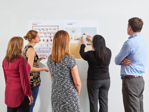 People gather to look at charts on a wall. 