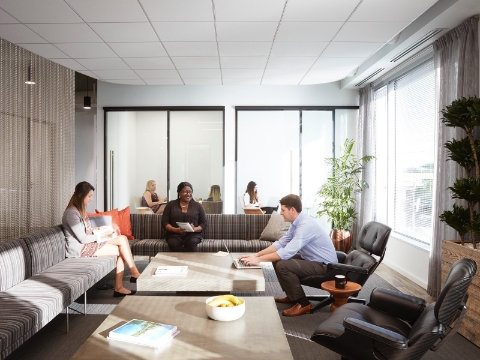 Three people sit in a lounge area with reclined chairs and couches. 