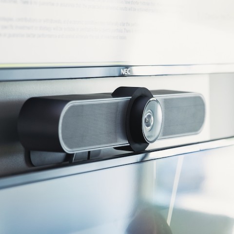 A close up of a wall-mounted camera above a monitor used for video conferencing.