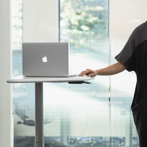 A person standing next to a height-adjustable Intent Solution cart with a laptop on it.
