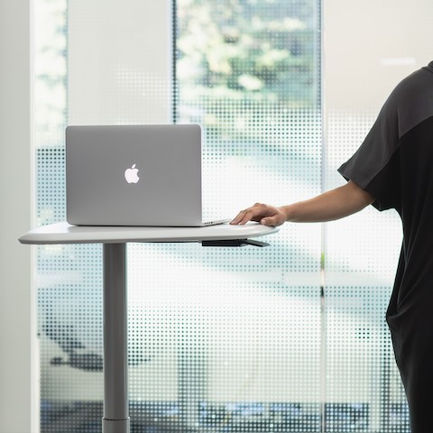 A person standing next to a height-adjustable Intent Solution cart with a laptop on it. A person standing next to a height-adjustable Intent Solution cart with a laptop on it.