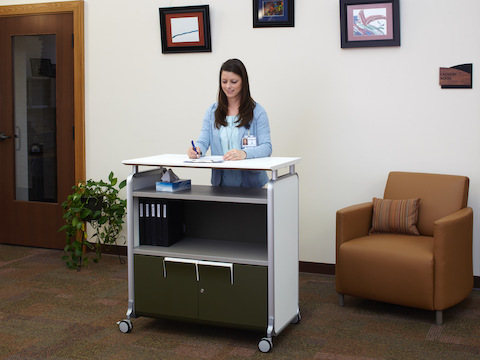 A staff member writes on a clipboard while standing next to a lounge chair. 