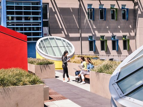 Three students talk while in an outdoor courtyard area.