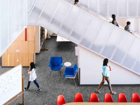 An open area inside of a school building with a large staircase. 