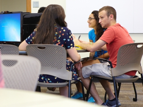 Students seated in Caper chairs converse with each other inside of a class. Students seated in Caper chairs converse with each other inside of a class.