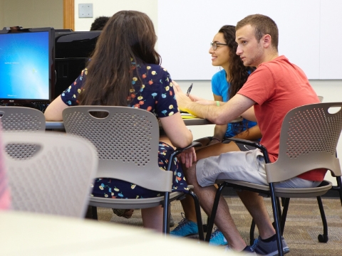 Students seated in Caper chairs converse with each other inside of a class. 