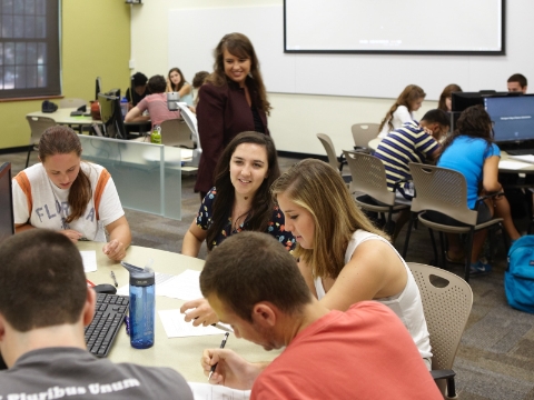 A classroom instructor interacts with groups of students seated in Caper chairs. 