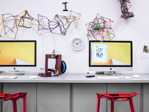 Computers sit on a wall-mounted desk, with art projects strewn above. Computers sit on a wall-mounted desk, with art projects strewn above.