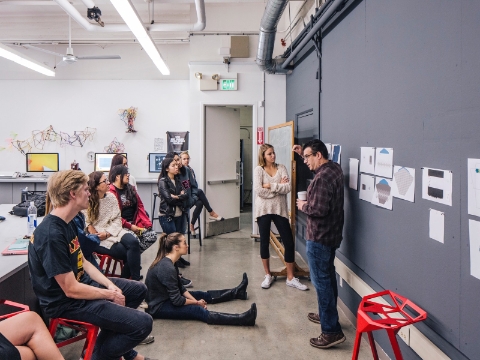 Students listen to an instructor inside of a college classroom. 