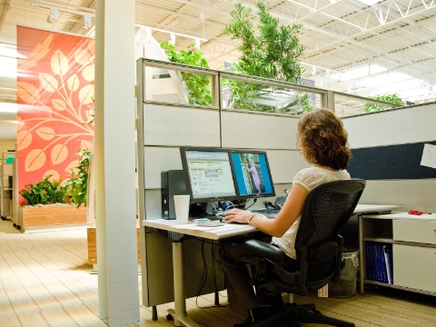 A woman conducts her work at a call center while seated in an Aeron chair. 