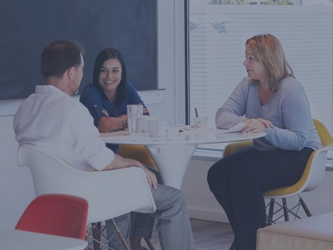 A trio of colleagues laugh and share stories during a coffee break. Their office is designed to build connections between people, connections that help improve employee retention.