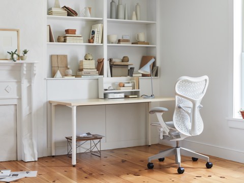 An all-white office with a white Mirra 2 Chair, white desk, Eames LTR table and bookshelves full of books and office accessories.