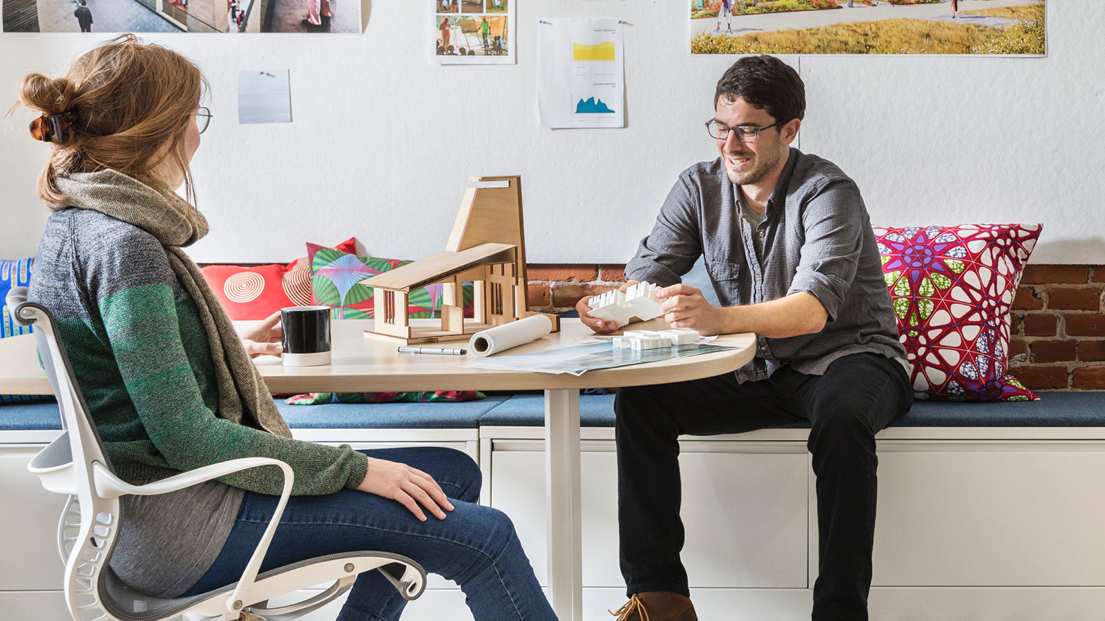 Two employees at MASS Design meet and chat in a collaborative space. Two employees at MASS Design meet and chat in a collaborative space.