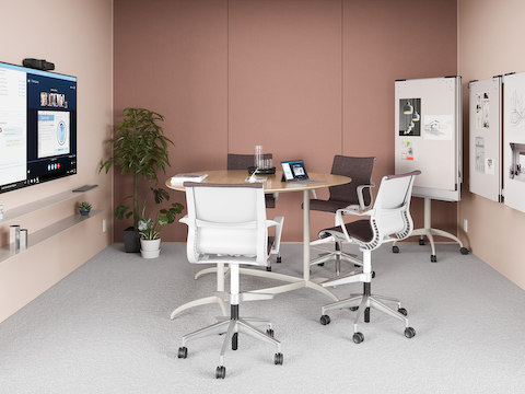 A light pink meeting space with a small table and Setu Stools, featuring the technology from Logitech.