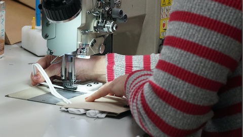 A Herman Miller employee sewing a face mask in a manufacturing space.