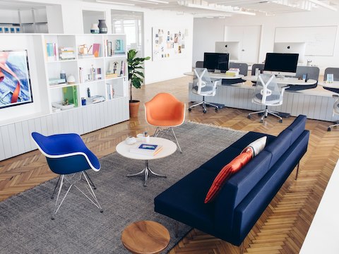 An office lounge seating area sits near several workstations in the background.