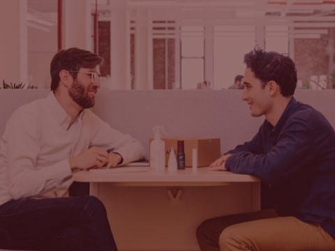 A pair of coworkers are having an impromptu meeting near the main work area. Thoughtfully designed settings such as these make it easier for people to meet and efficiently solve problems.