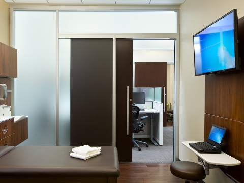 A medical exam room sits empty with two towels on the bed. 