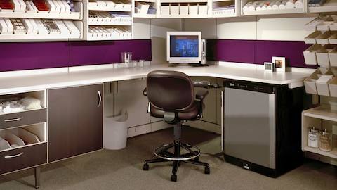 An Ergon chair sits at a workdesk inside a neat and orderly prescription medication office. 