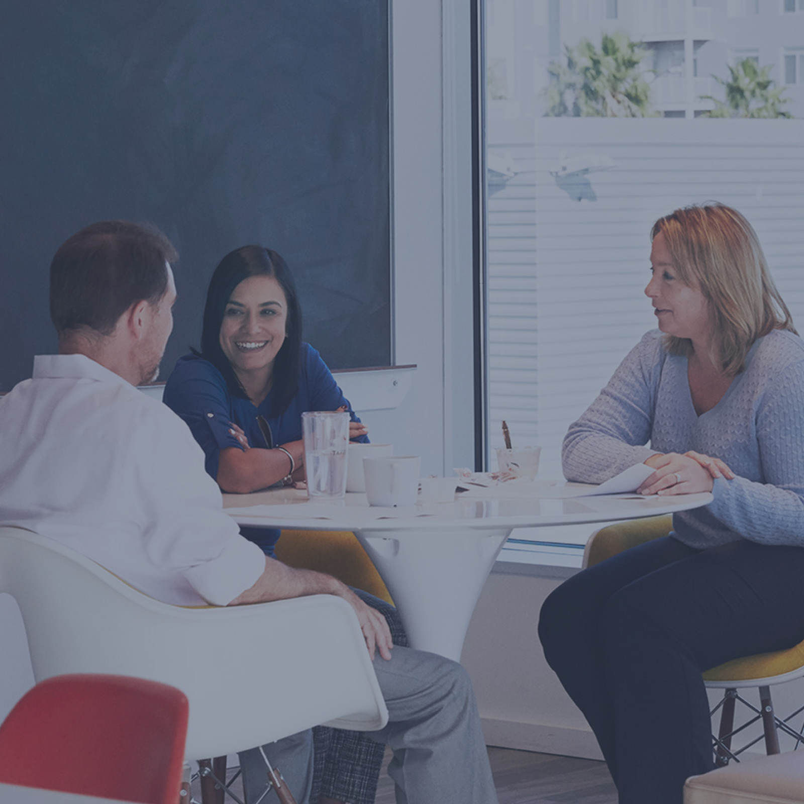 Un trio de collègues en train de rire et de partager des anecdotes lors d’une pause café. Leur bureau a été conçu pour créer des connexions entre les gens, ce qui contribue à son tour à la rétention du personnel.