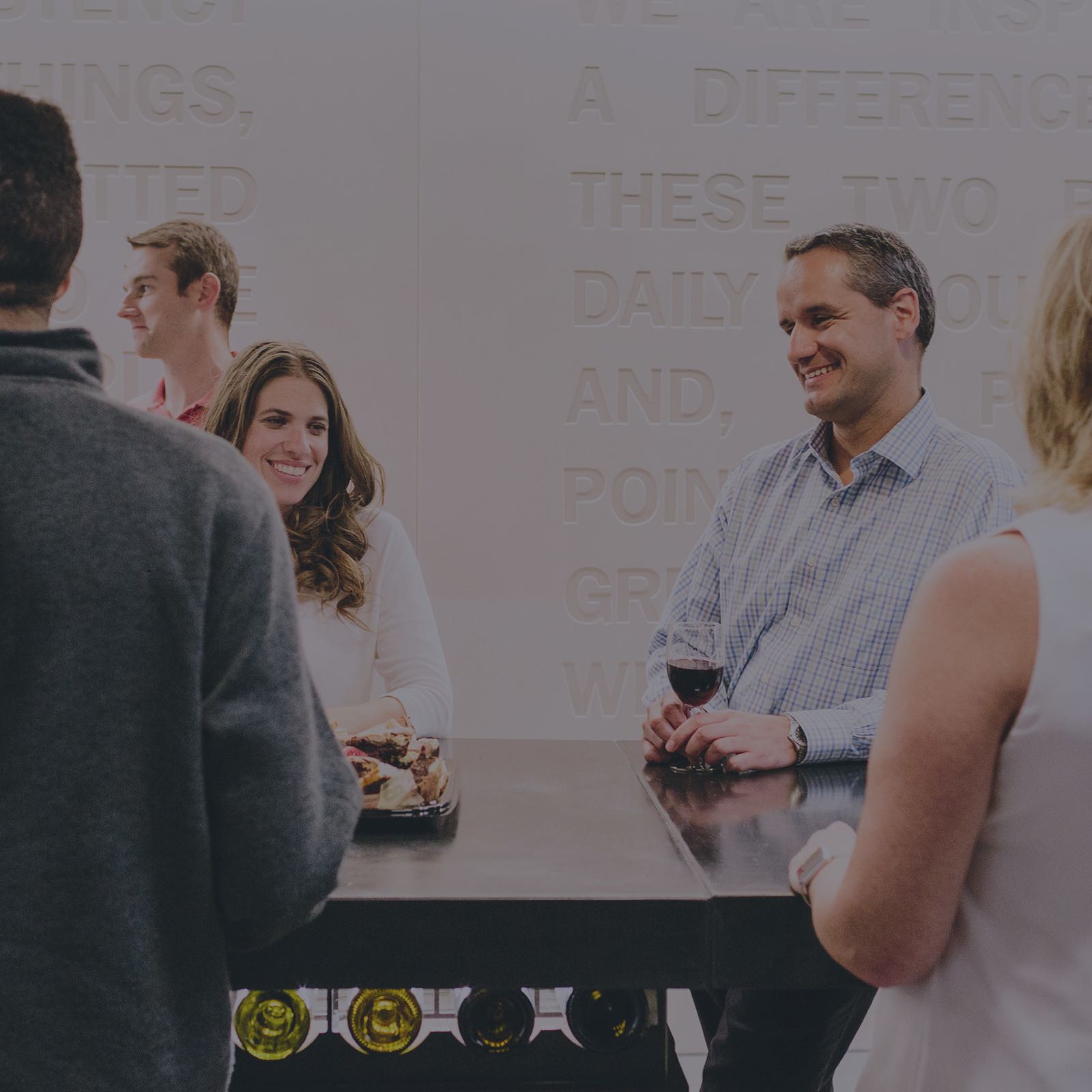 Een groepje collega's verzamelt zich rond een hoge tafel in hun kantoor voor een sociale ontmoeting na het werk. Dit soort informele bijeenkomsten bevordert innovatie.