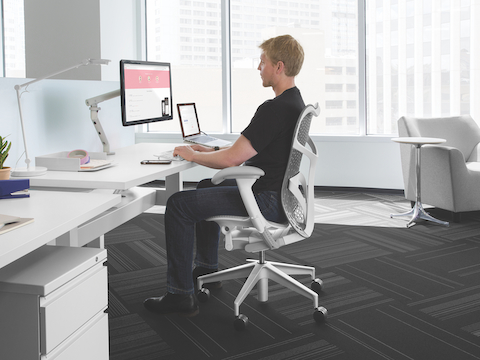 Profile view of a man in a Mirra 2 office chair viewing a monitor attached to an adjustable arm. Profile view of a man in a Mirra 2 office chair viewing a monitor attached to an adjustable arm.