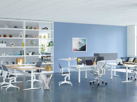 A collaboration setting featuring a cluster of sit-to-stand desks and a rectangular table from Atlas Office Landscape. A collaboration setting featuring a cluster of sit-to-stand desks and a rectangular table from Atlas Office Landscape.