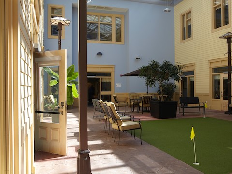 An indoor lounge area with natural light and a putting green surface. An indoor lounge area with natural light and a putting green surface.