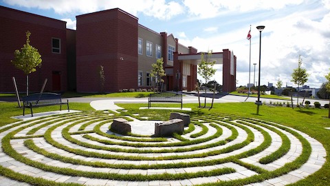 An exterior view of an assisted care center, with a circular stone path in the foreground. 