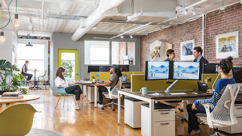 People working and collaborating at their desks in an open office setting.