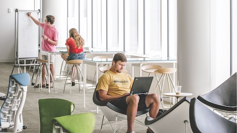Three college students work in a study area featuring blue and green Embody Chairs. Three college students work in a study area featuring blue and green Embody Chairs.