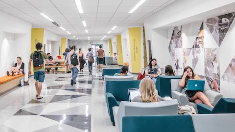 Studenten in einem Korridor mit Wandbänken und Lounge-Sitzplätzen.