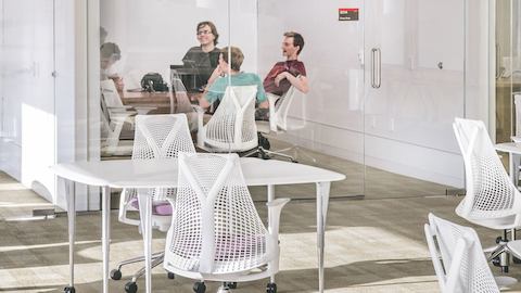 Students converse while in an enclosed room within a campus library.