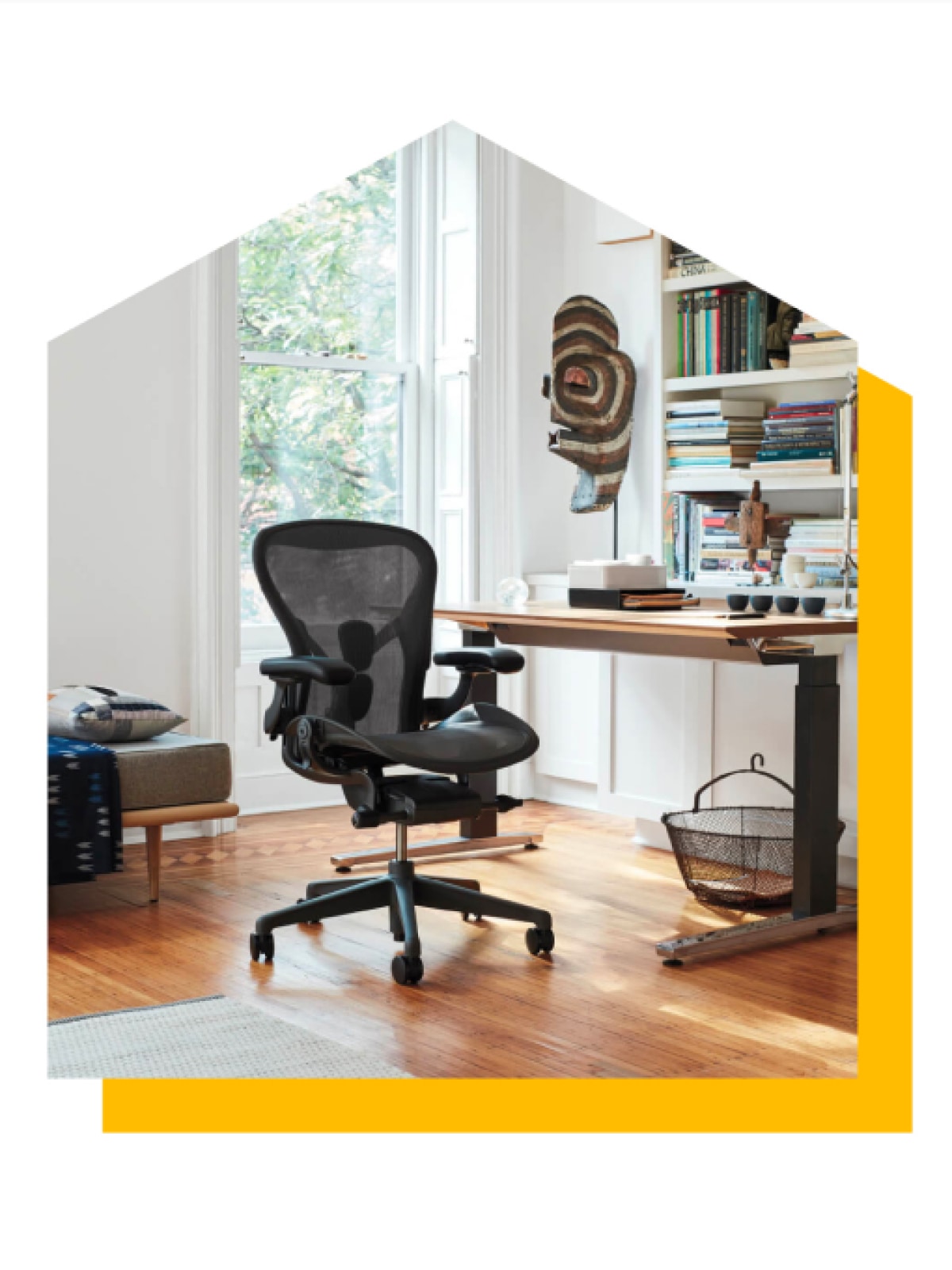 坐姿-站姿切换两用办公桌的旁边有一张石墨黑色的Aeron座椅。图片被剪辑成房屋形状，背后有一个亮黄色的水滴阴影。