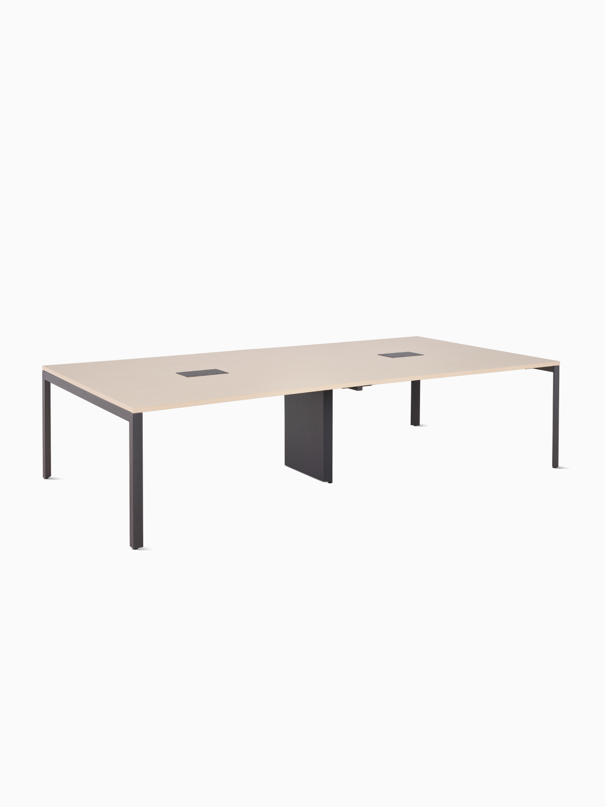 A Herman Miller Layout Studio project table with an ash woodgrain laminate top, two central power integration ports, and a graphite base, viewed at an angle.