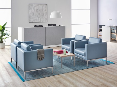 A healthcare reception area featuring four light blue lounge chairs. 